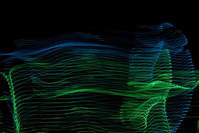 light dance image in green and blue, two figures thriving, their clothes blowing in the wind, image by Charlie Alice Raya